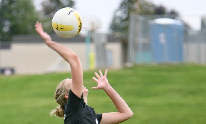 girl serving a volleyball outdoors
